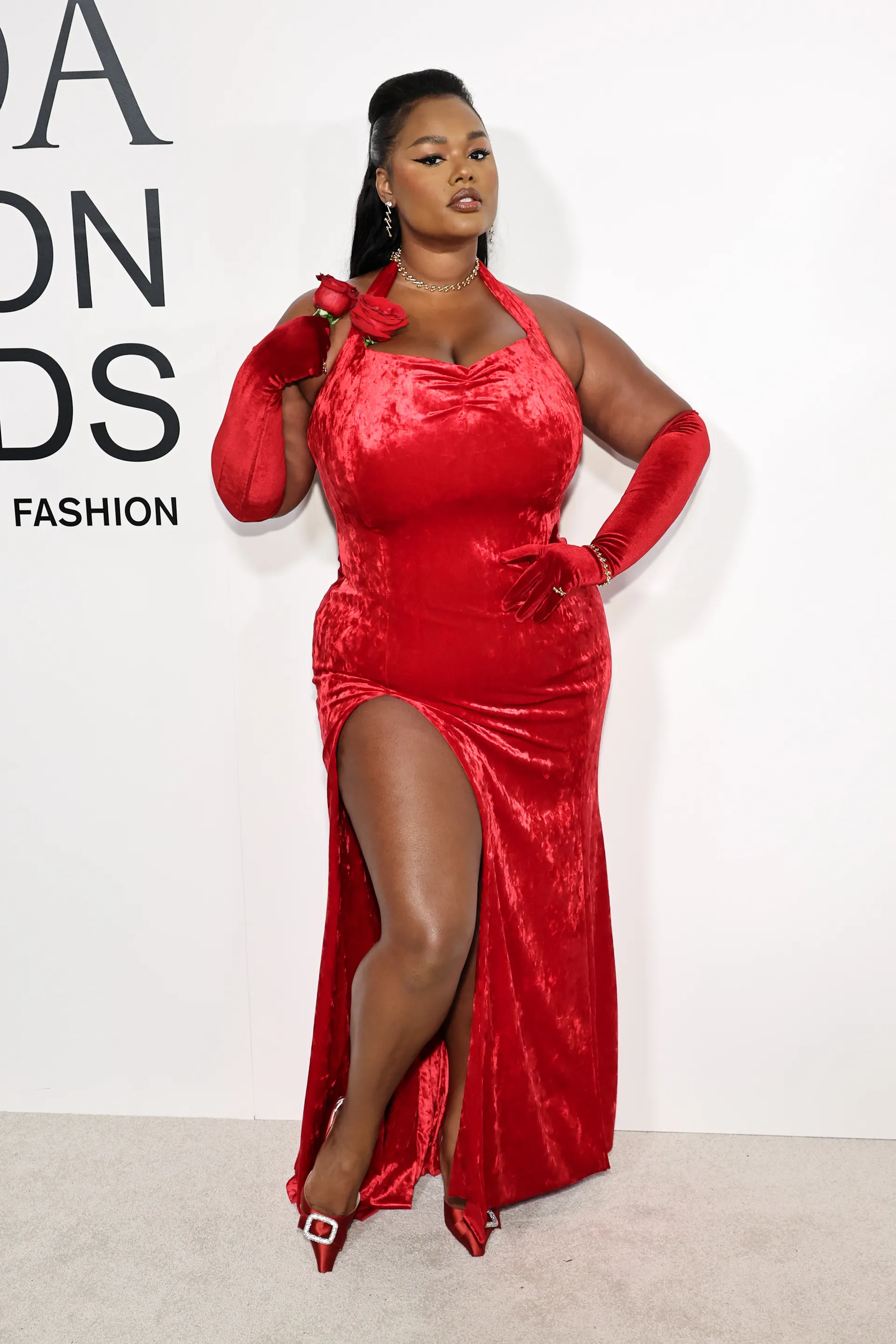 Modelo em vestido de veludo vermelho com luvas longas na cerimônia CFDA Fashion Awards 2024.