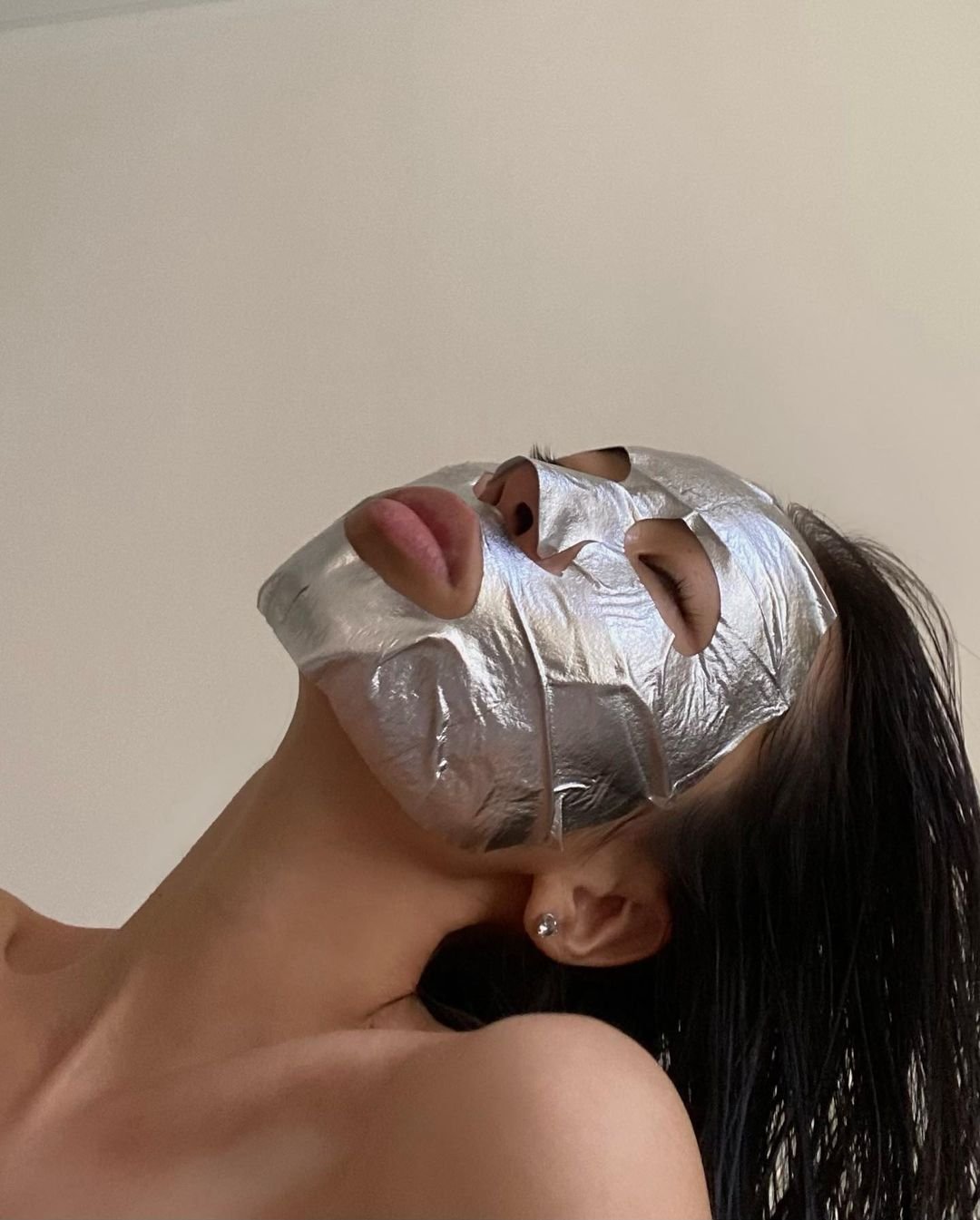 Pessoa utilizando máscara facial de tratamento metálica, tendência de skincare moderna. O visual reflete cuidado pessoal e estética futurista, comum em rituais de beleza contemporâneos. Destaca-se pela simplicidade e sofisticação. spa em casa