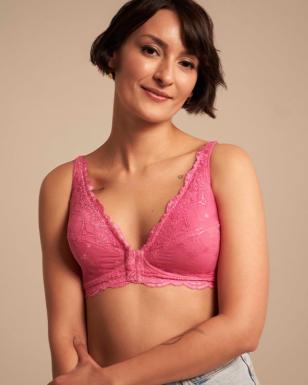 Mulher usando um bralette rosa de renda, tendência atual na moda íntima, destacando conforto e estilo. A peça é combinada com uma calça jeans clara, criando um visual casual e moderno.