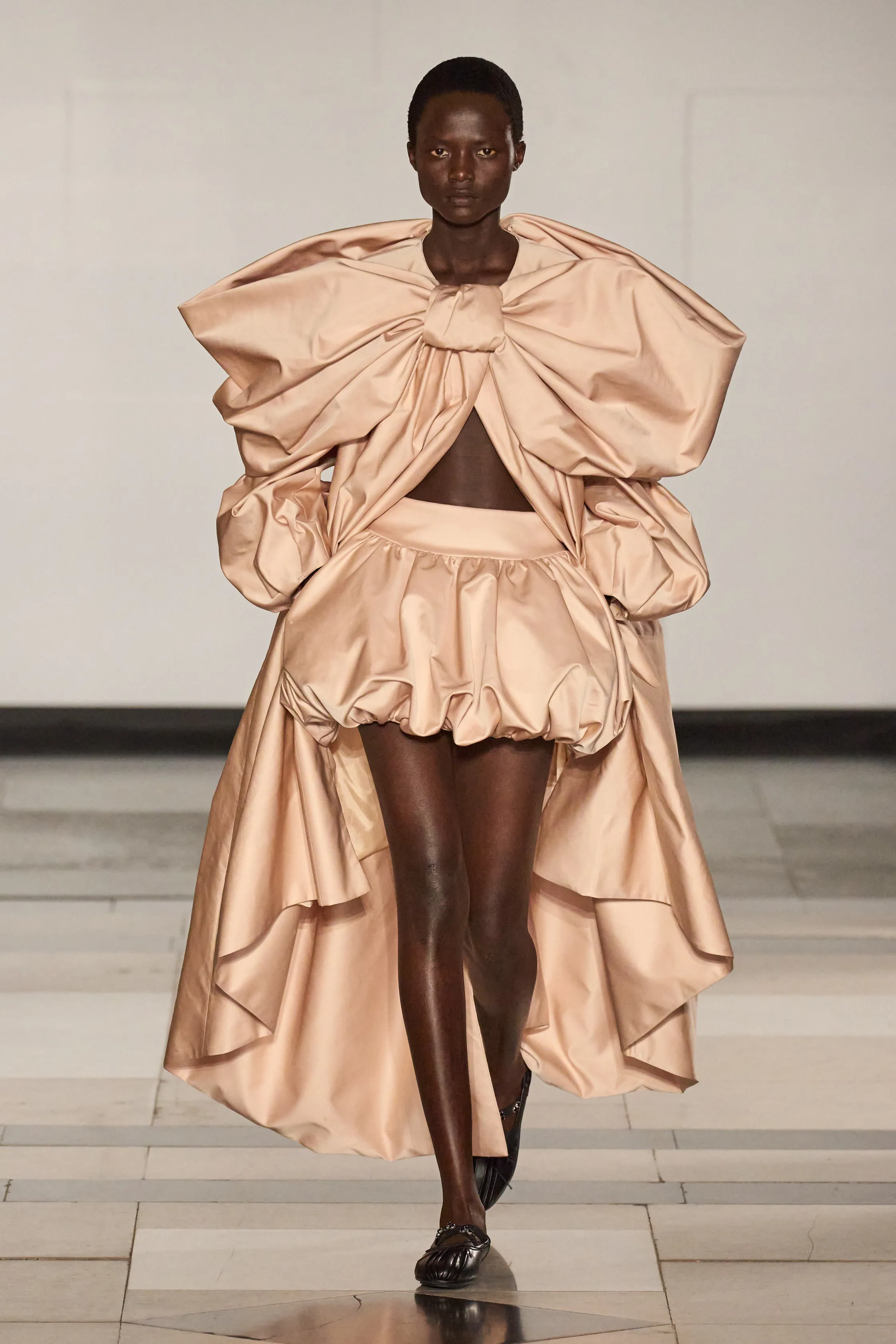 Modelo veste roupa extravagante em desfile, representando tendências ousadas na moda.