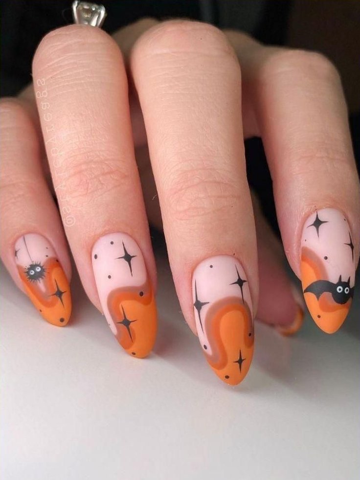 Unhas de Halloween, com design laranja e preto. Tendência de nail art com detalhes de morcegos e estrelas, ideal para festas temáticas. Visual moderno e criativo, valorizando estilo e originalidade.