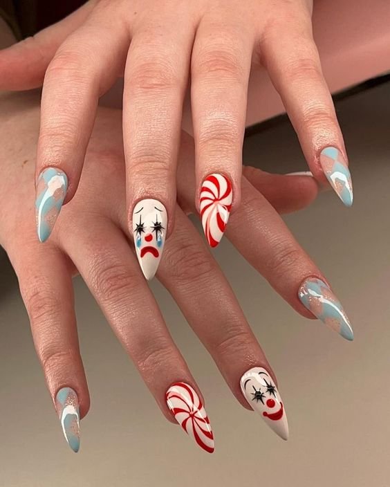 Unhas de halloween com nail art criativa e moderna: desenhos de palhaço e listras vermelho-branco, combinados com efeitos em azul. Tendência ousada e divertida, ideal para quem busca destacar-se com elementos artísticos.