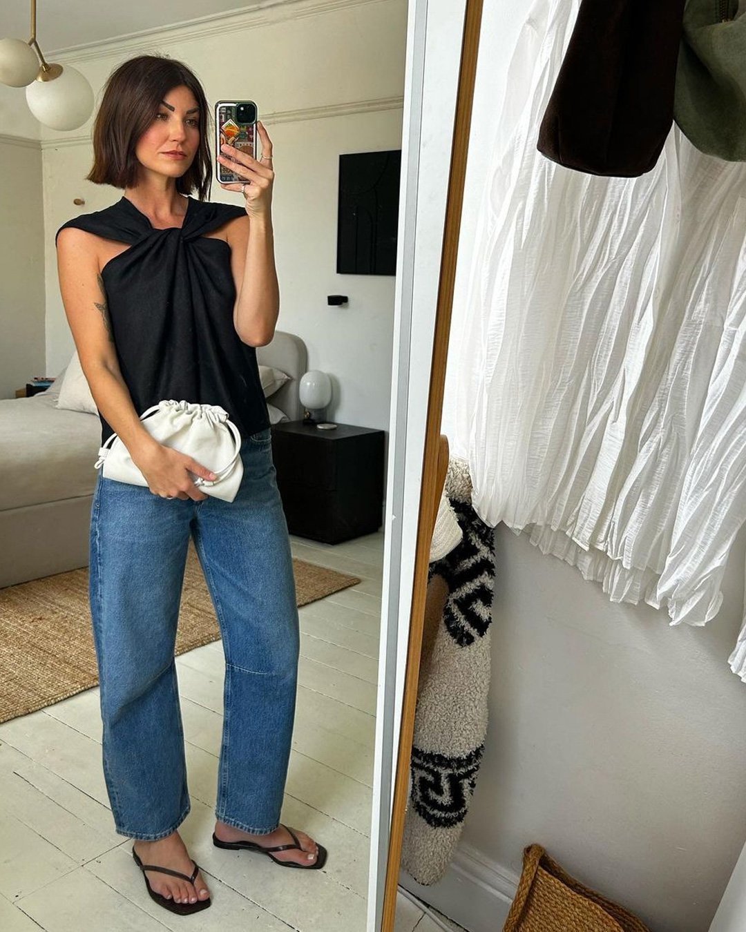 Mulher com blusa preta e jeans segura uma das bolsas pequenas da moda tendência.