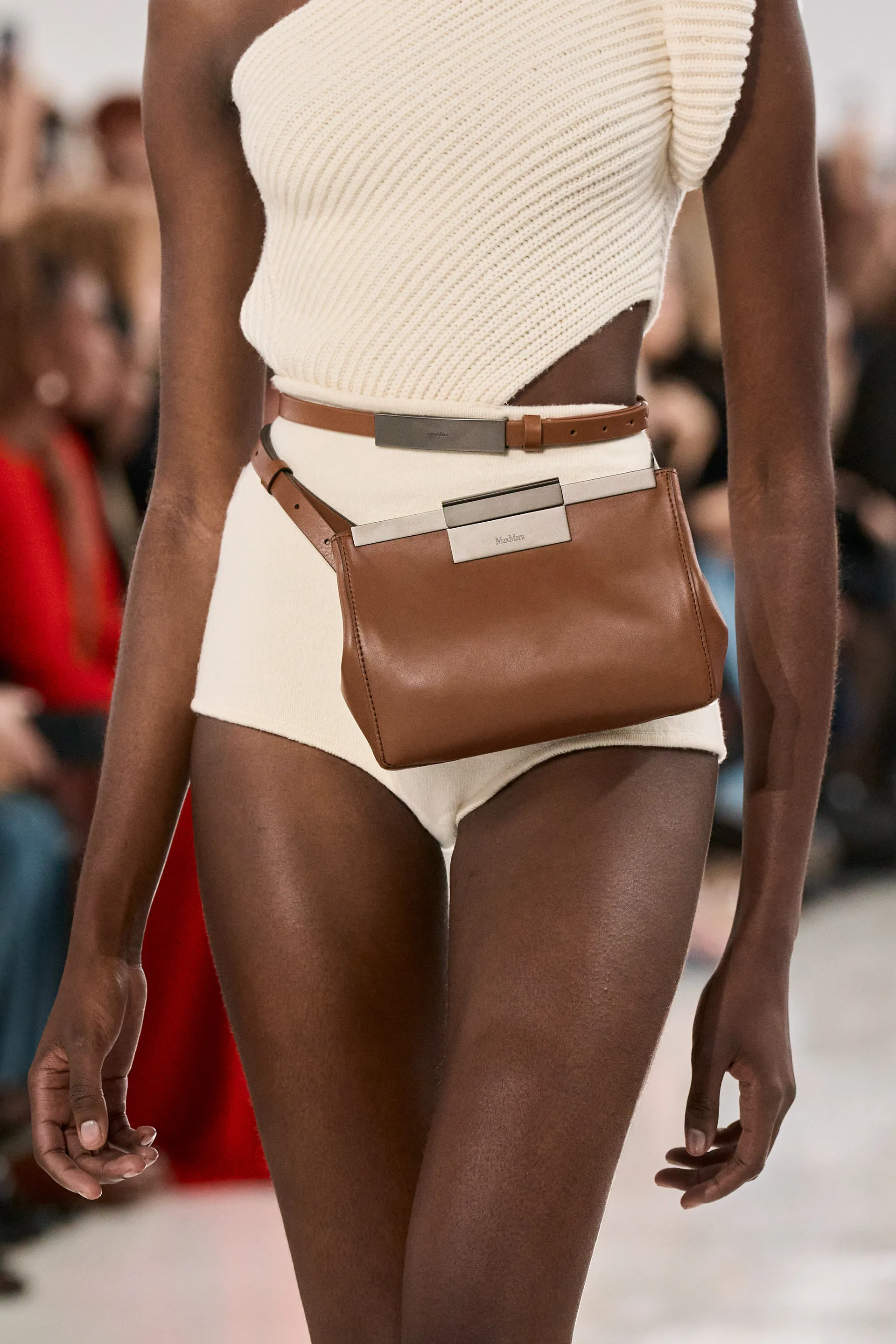 Cintos tendência elegante com bolsa marrom complementa look de moda em desfile, destacando tendências contemporâneas.