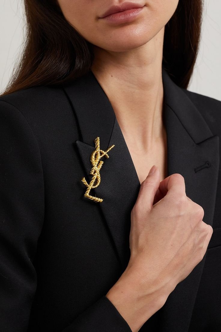 Dourado sofisticado destaca-se em blazer preto, broche estiloso realça elegância moderna.