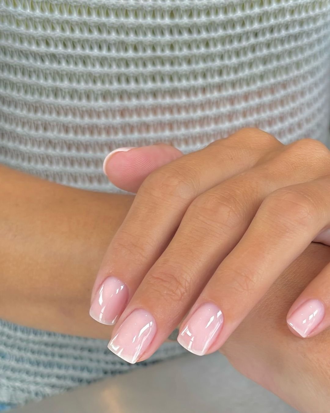 Unhas curtas e naturais com esmalte rosa claro, refletindo tendências de unhas de 2025.