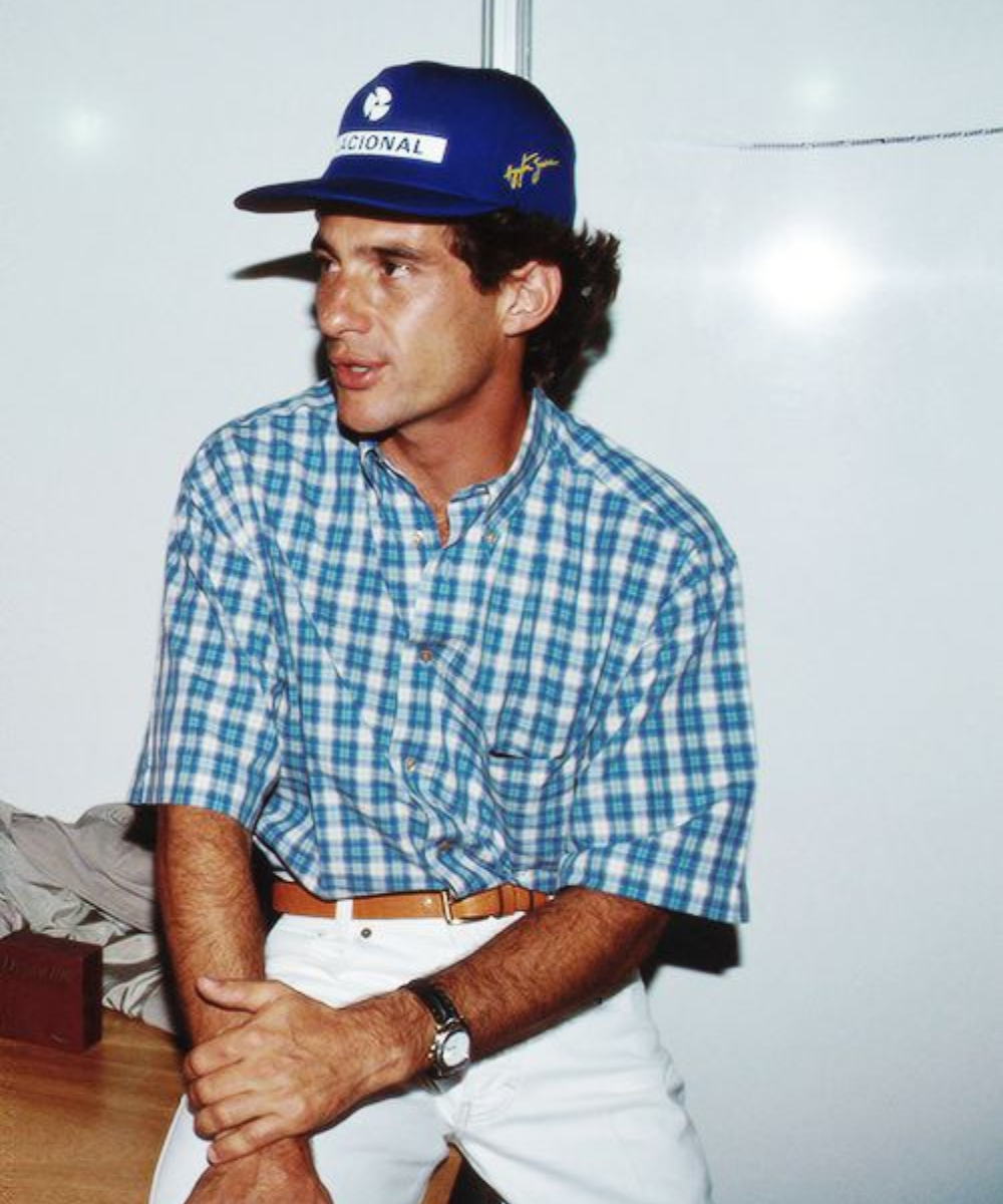 Homem com boné azul e camisa xadrez, estilo descontraído e casual.