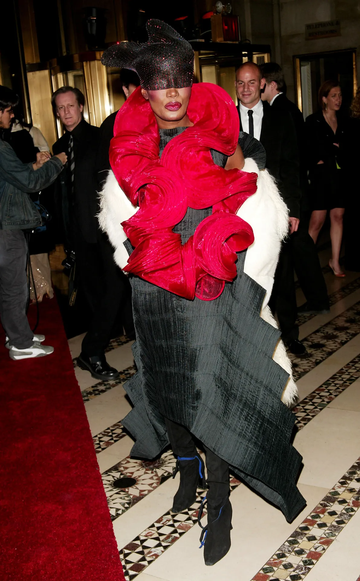 Vestido extravagante com ondas vermelhas e pretas, usado por Grace Jones em evento sofisticado.