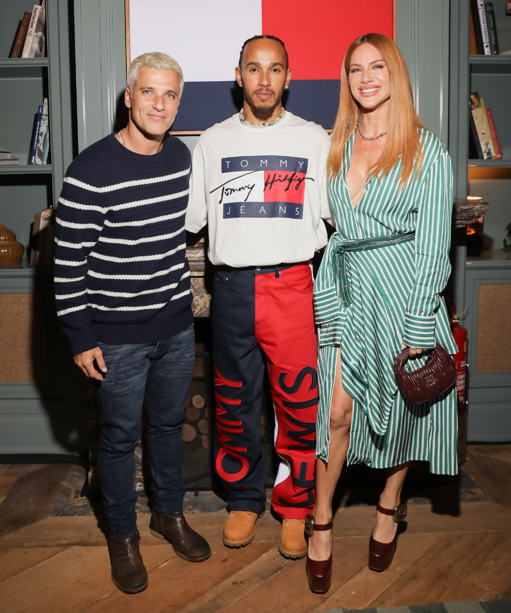 Três pessoas sorrindo juntas, uma delas usando calça com logo da Tommy Hilfiger. Participantes do evento GP de São Paulo.