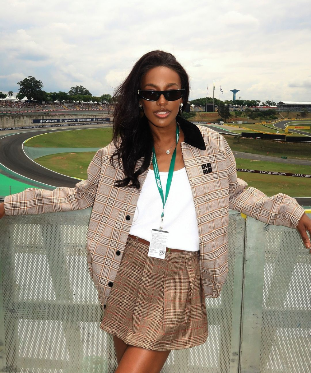 Mulher com óculos de sol e roupa xadrez em frente a pista de corrida do GP de São Paulo 2024.