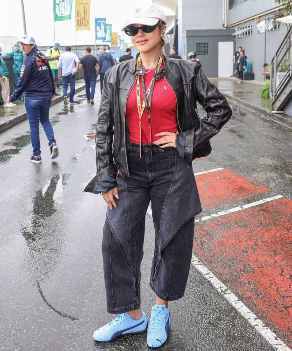 Pessoa com jaqueta de couro e boné branco em pista molhada antes do GP de São Paulo 2024.