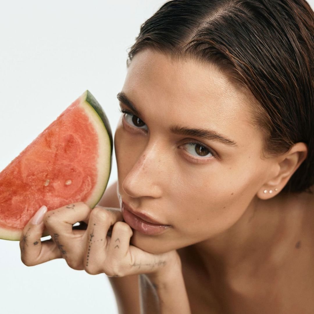 Mulher segurando uma fatia de melancia perto do rosto, destacando a essência de Produtos com cheiro de frutas.