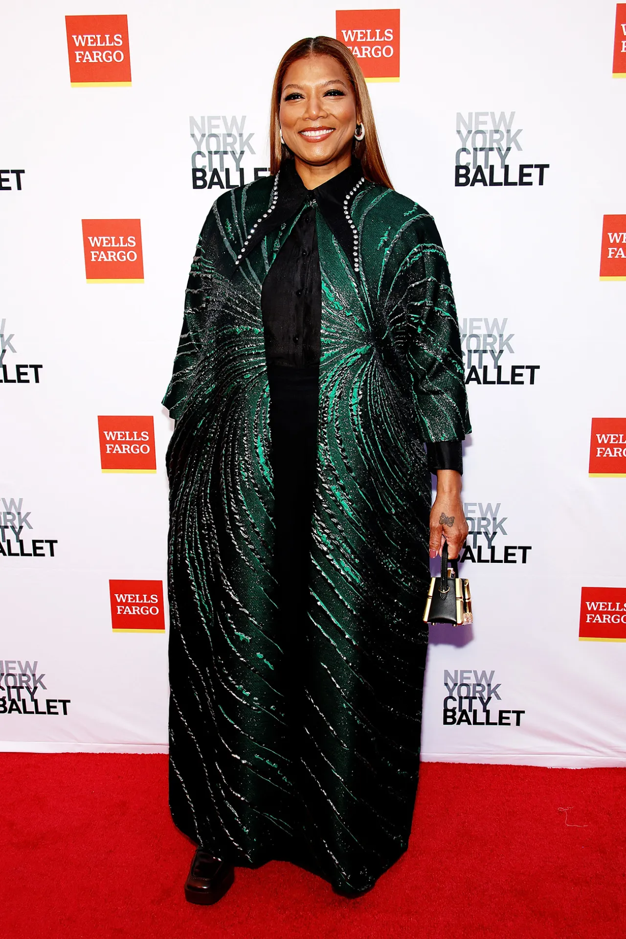 Pessoa em um evento do New York City Ballet, usando um elegante casaco verde.