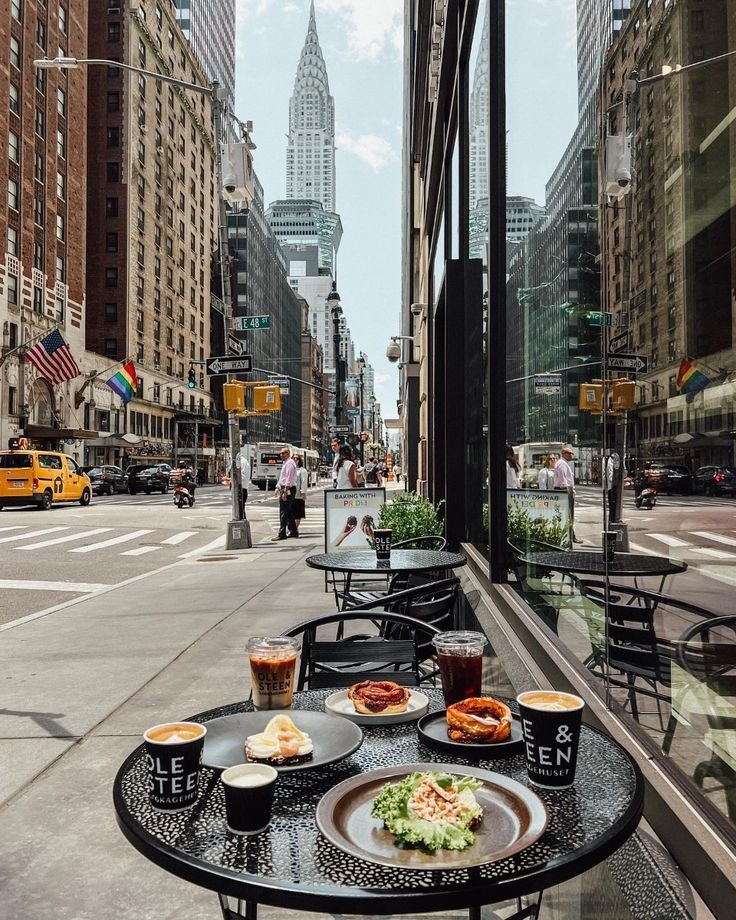 Mesa de café na calçada com salada e bebidas em uma cidade movimentada, perto de locais dos melhores restaurantes veganos.