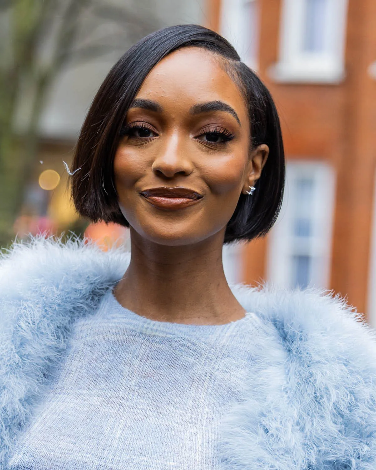 Mulher sorridente com cabelo bob, estilo popular em cortes de cabelo em 2025, usando roupa azul texturizada.