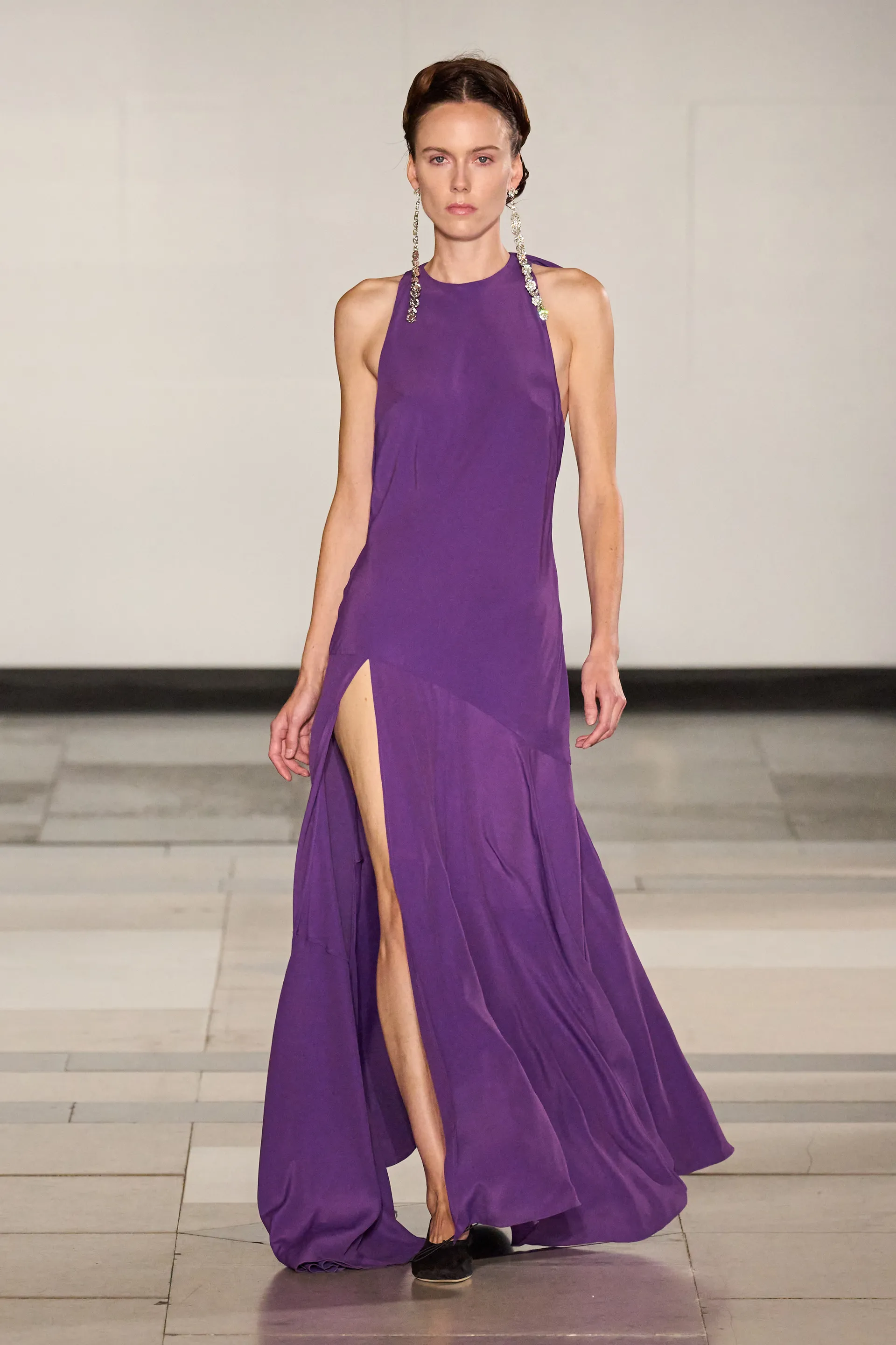 Vestido longo roxo com fenda, tendência das cores do verão 2025, em desfile de moda.