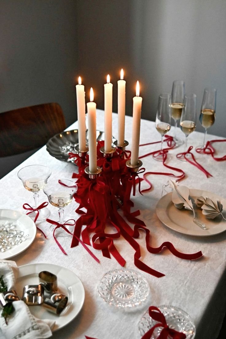 mesa de réveillon decorada com velas e laços vermelhos