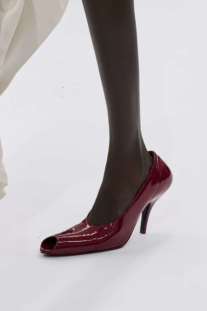 Sapato peep toe vermelho com salto fino, destacando-se em um fundo claro.