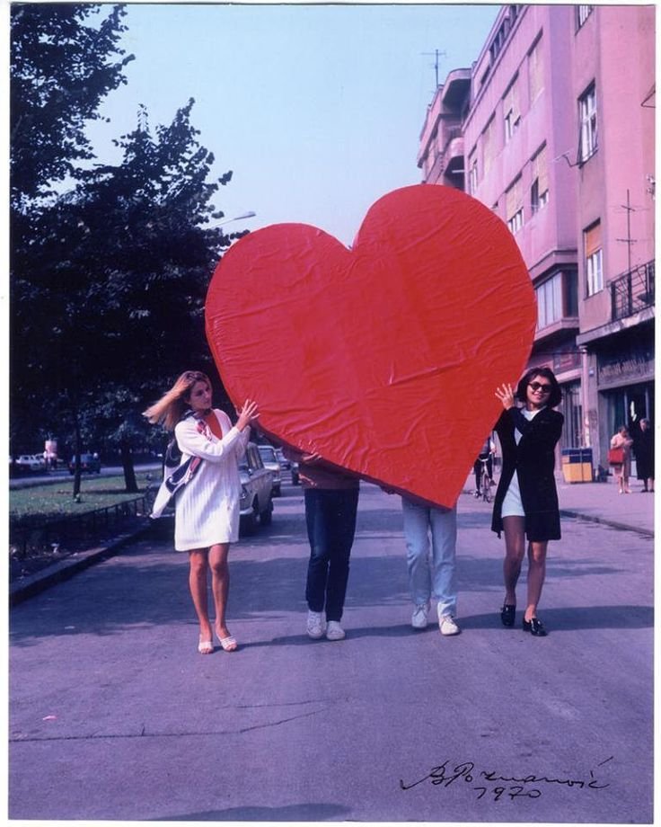 Grupo carrega enorme coração vermelho em rua urbana, simbolizando amor em 2025.