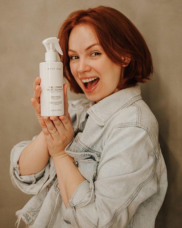 Pessoa feliz segurando produto para cabelo, potencialmente parte de um Kit de final de ano, vestindo jaqueta jeans.

