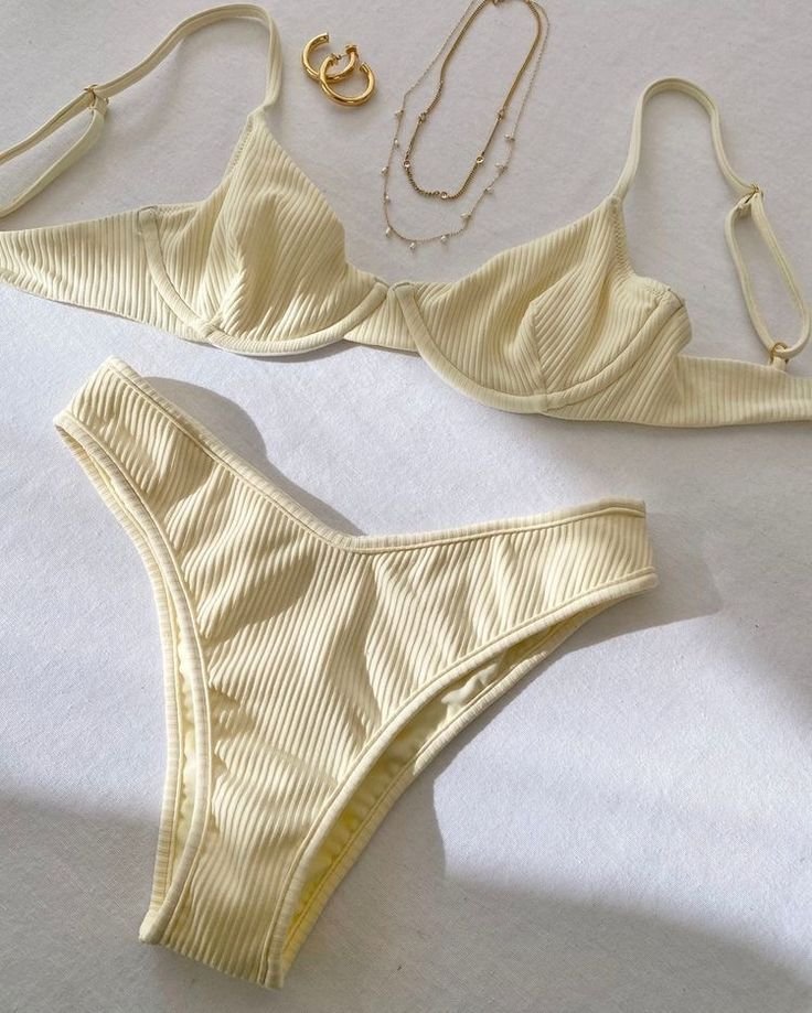 Conjunto de lingerie bege com detalhes em dourado ao lado.