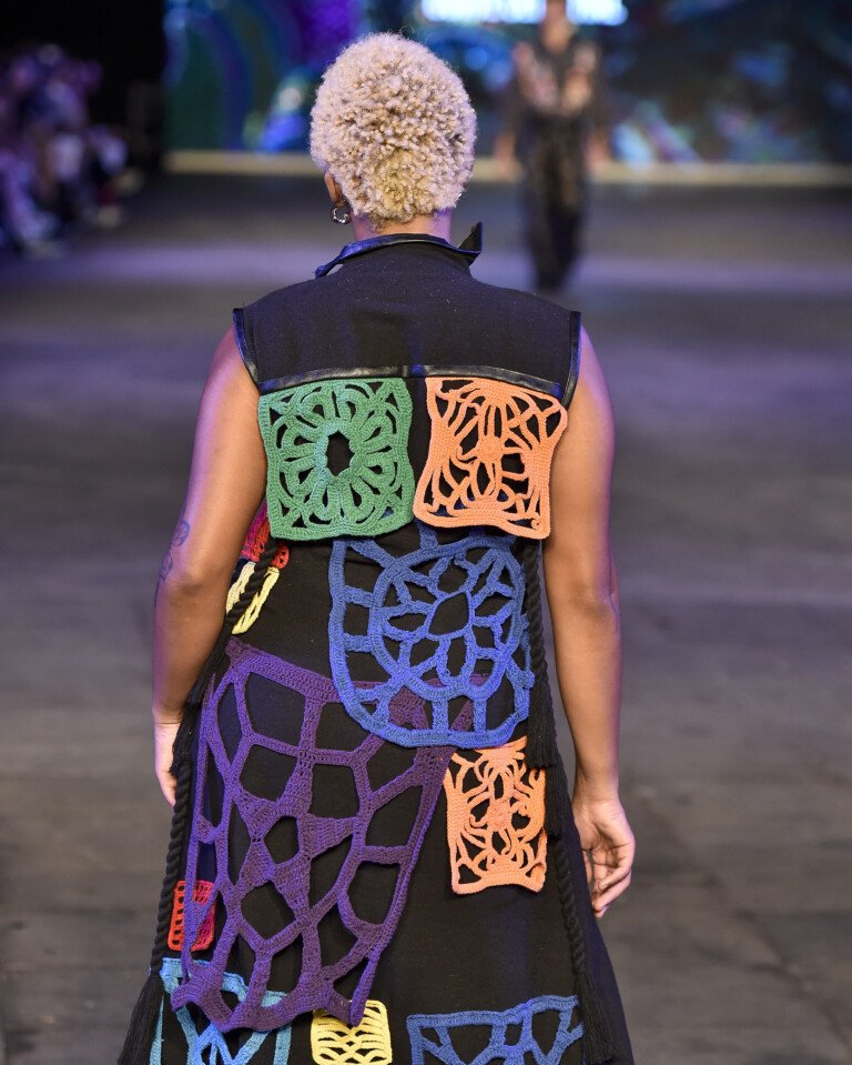 Desfile de moda com modelo vestindo roupa com patchwork colorido em tecido.