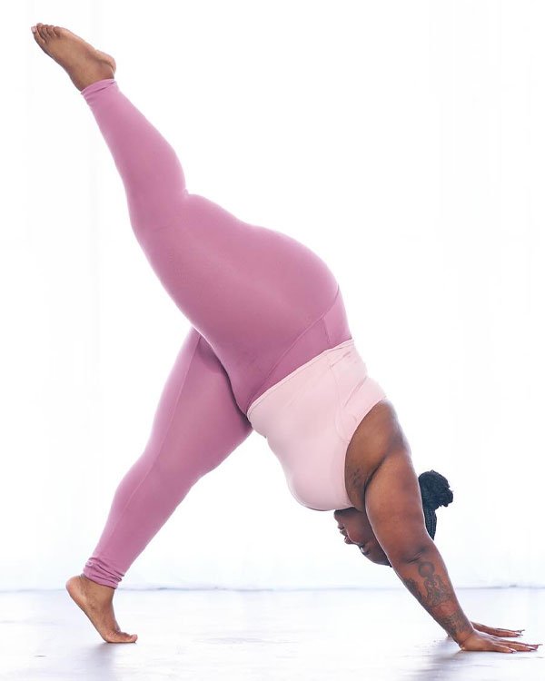 Pessoa realizando yoga em um look de academia rosa, equilibrada em posição de alongamento com a perna elevada.