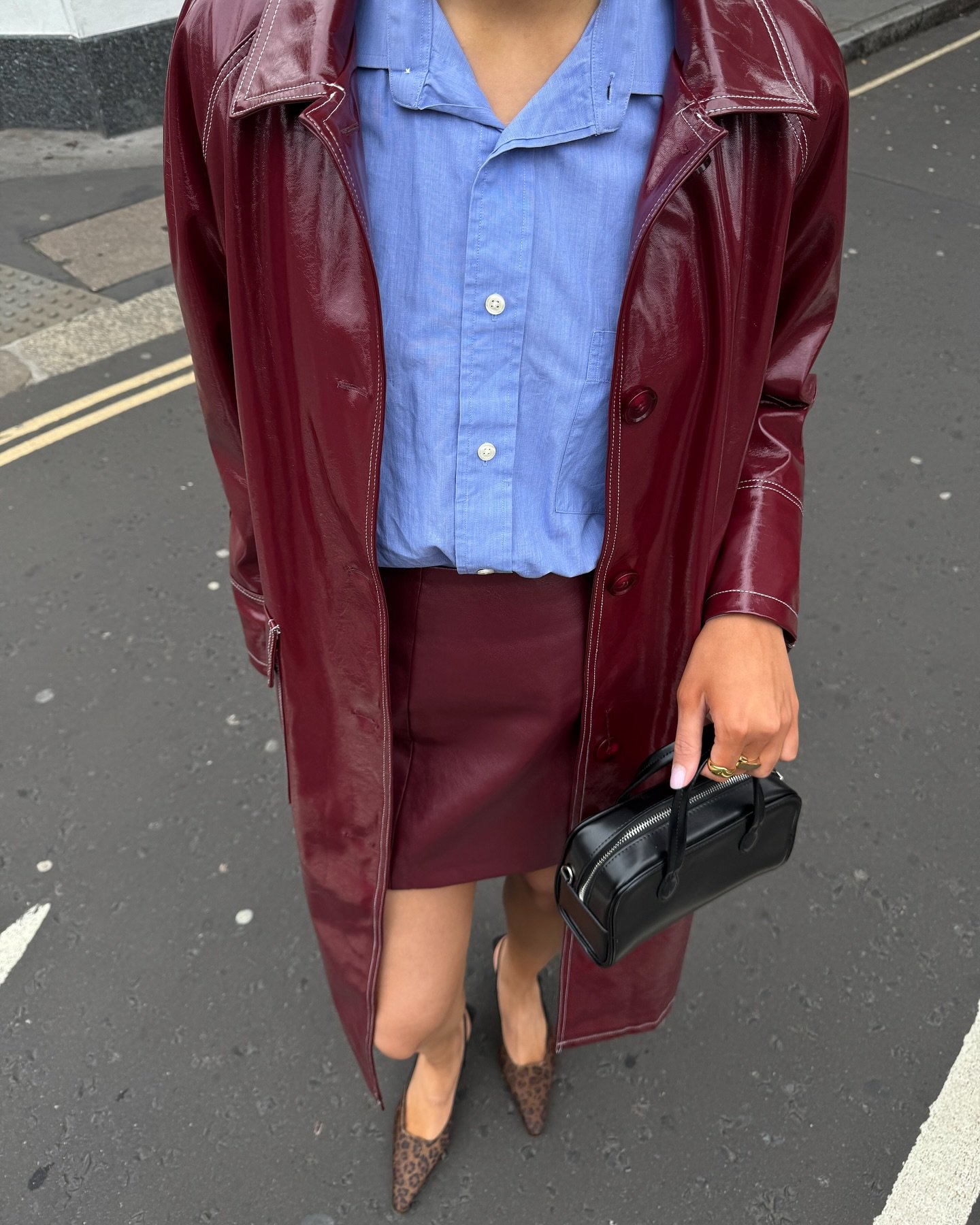 Pessoa usando casaco vinho, camisa azul e saia combinando, com bolsa preta. Cores da moda destacadas.