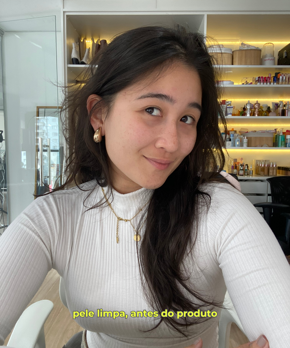 Mulher sorrindo em um escritório, com pele limpa e preparada para aplicação de Glazing Milk.