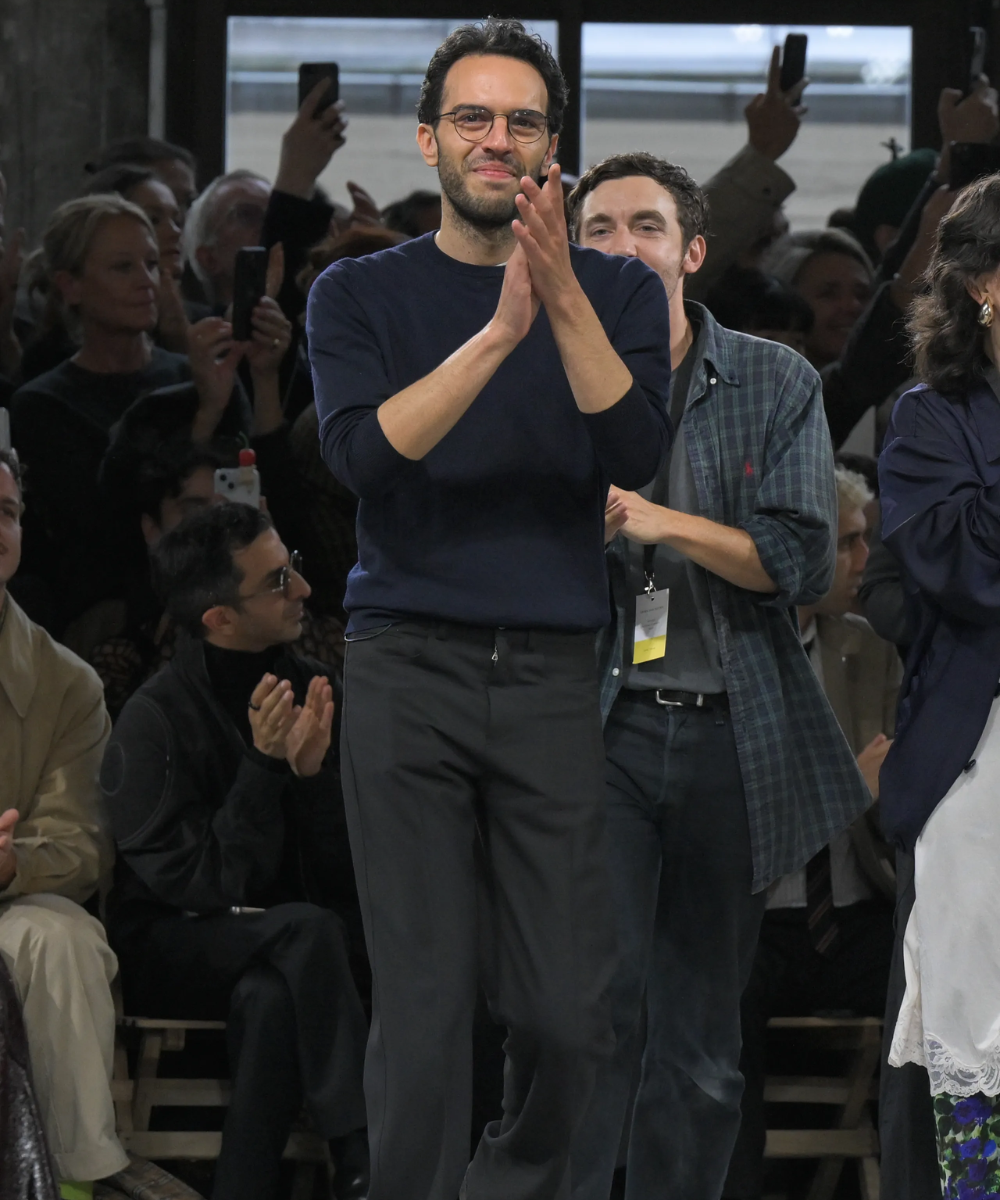 Desfile de moda com aplausos entusiasmados, simbolizando a dança das cadeiras da moda.