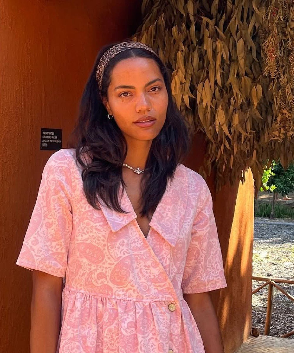 Mulher usando vestido rosa e faixa no cabelo sob luz do sol.  penteados fáceis para o Natal