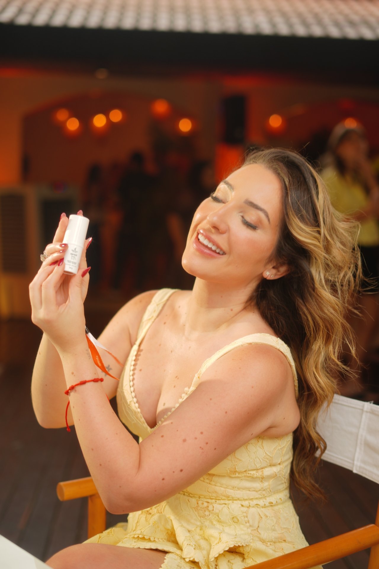 Pessoa segurando um protetor solar stick com cor, sorrindo enquanto aprecia o produto em um ambiente descontraído.