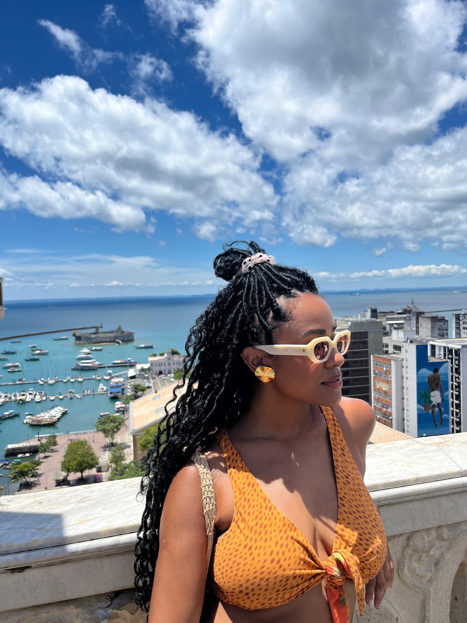 Pessoa com óculos de sol apreciando a vista de um cais em dia ensolarado em salvador, bahia, brasil.
Réveillon na praia