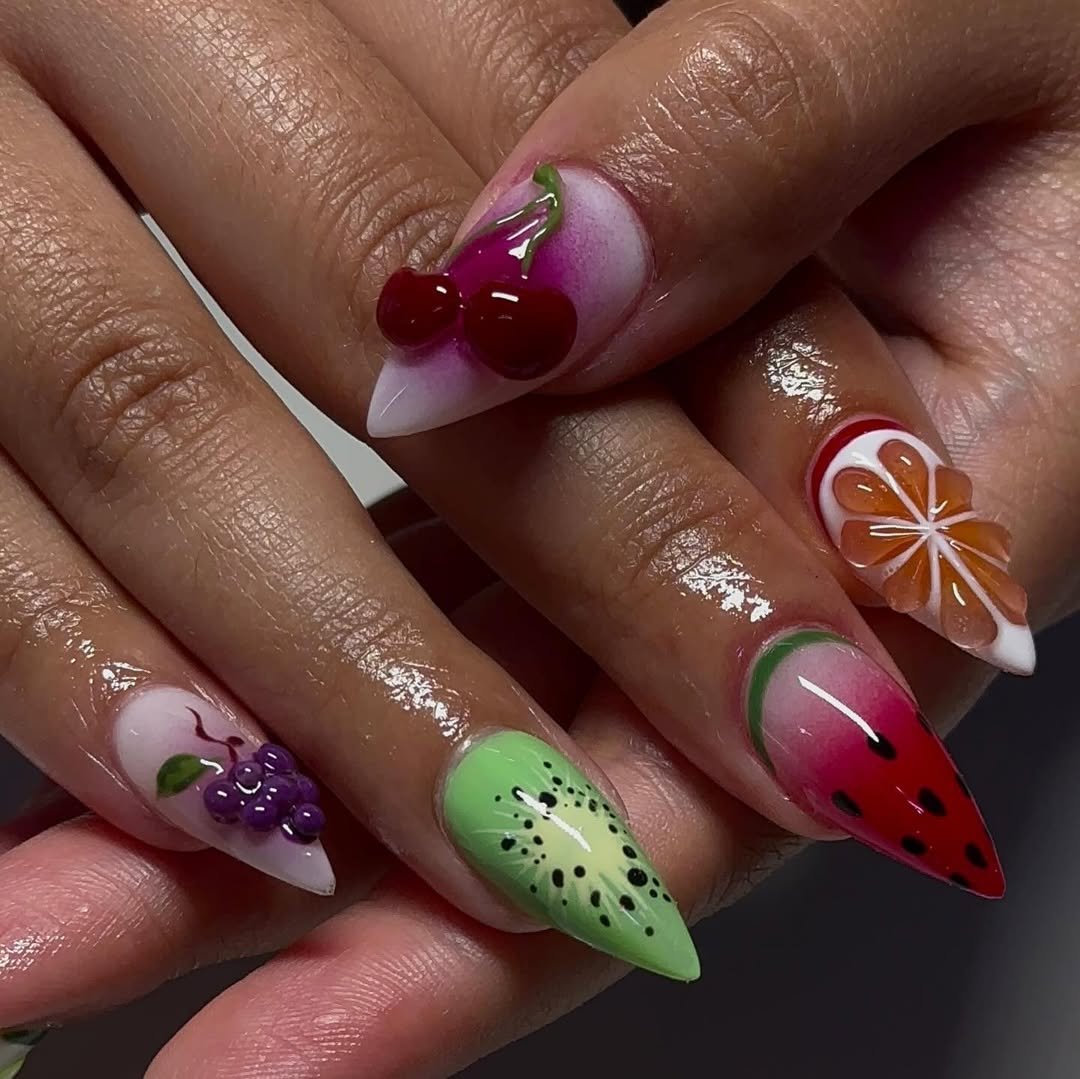 Unhas decoradas com frutas coloridas em 3D, inspiradas nas tendências de beleza de 2024.