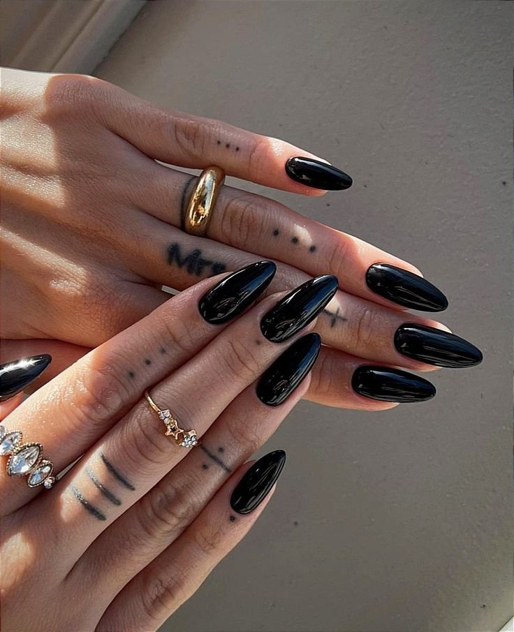 Unhas pretas decoradas com anéis, tendência elegante de unhas para Ano Novo 2025.