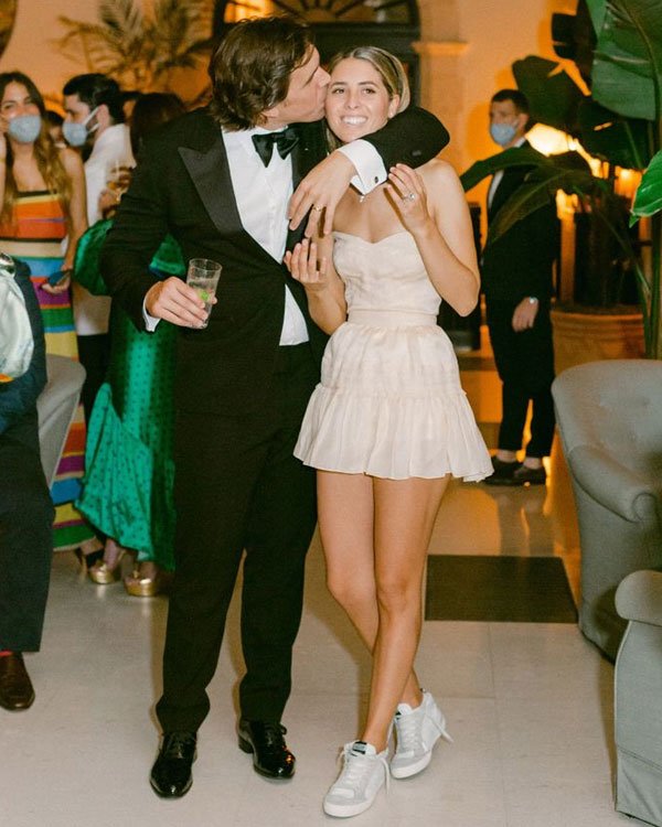 Casal em festa elegante; mulher em vestido curto e tênis, combinação perfeita para cada ocasião.