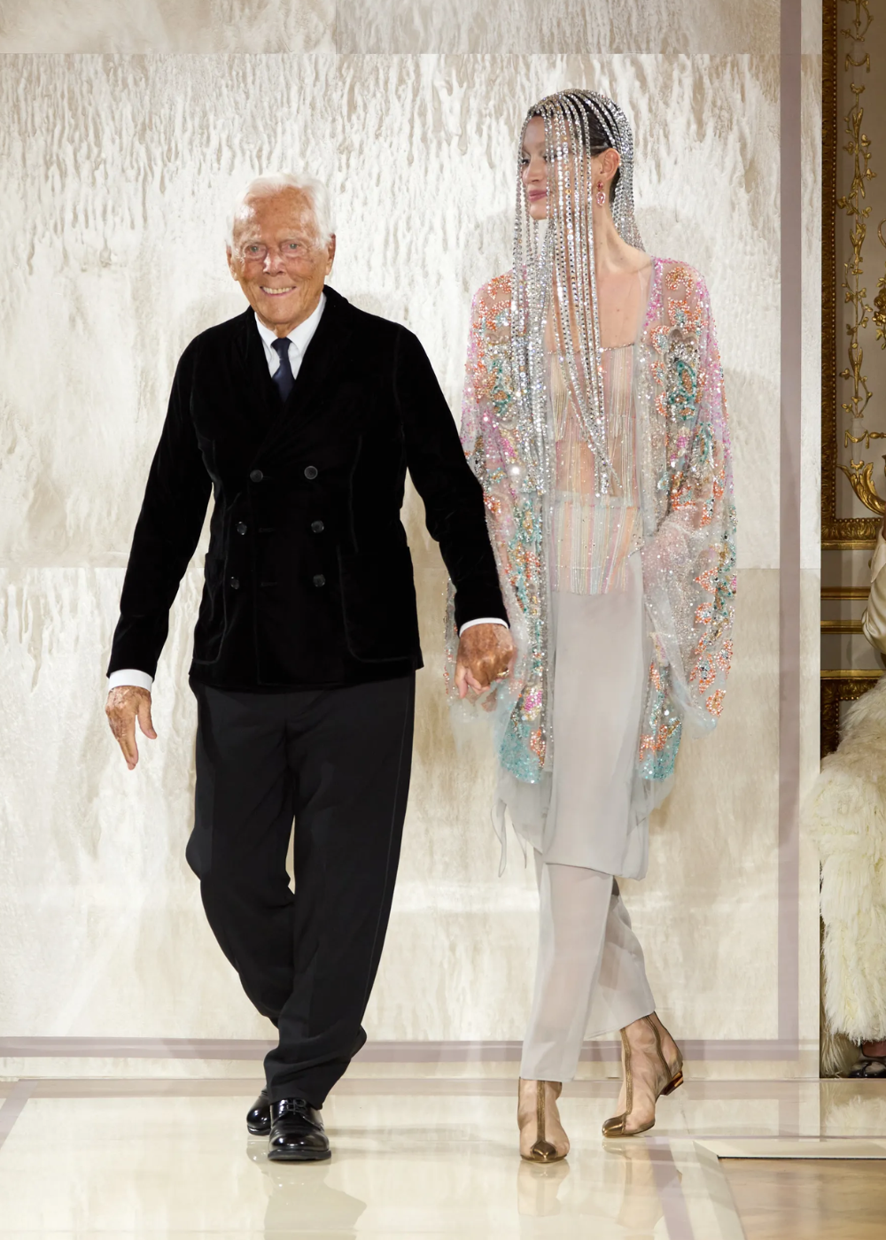 Estilista com modelo exibindo roupa glamourosa com cristais na Semana de Alta-Costura 2025.
