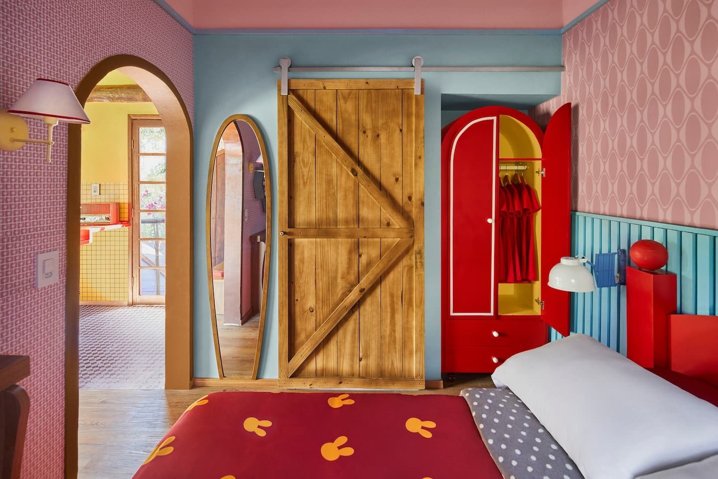 Quarto com decoração vibrante, porta de madeira rústica e armário vermelho. Estilo casas temáticas lúdico.