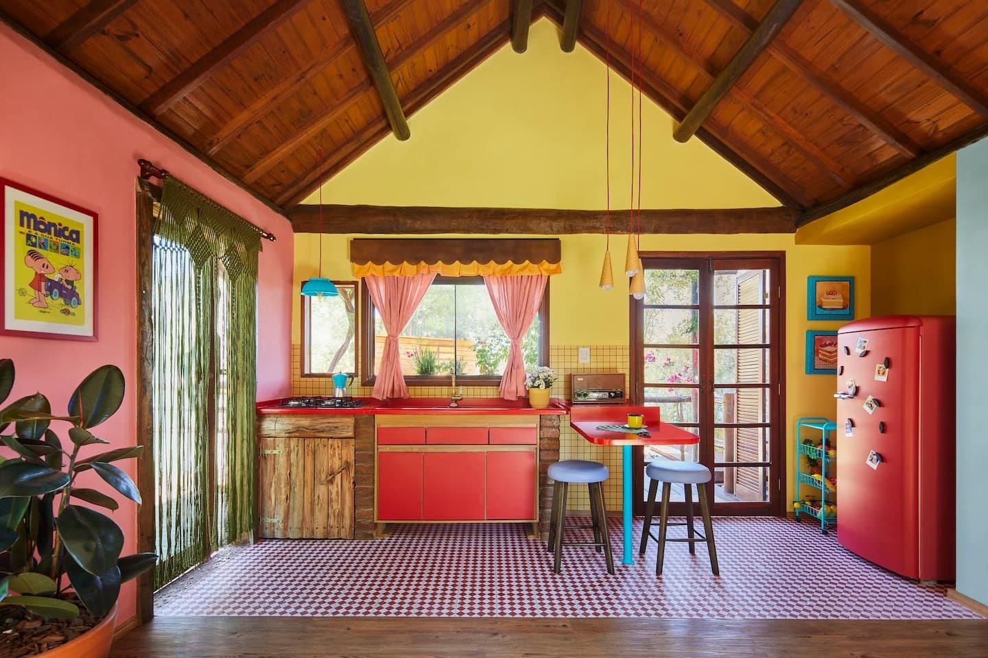 Cozinha temática colorida com geladeira vermelha, móveis de madeira e decoração inspirada em quadrinhos na parede.