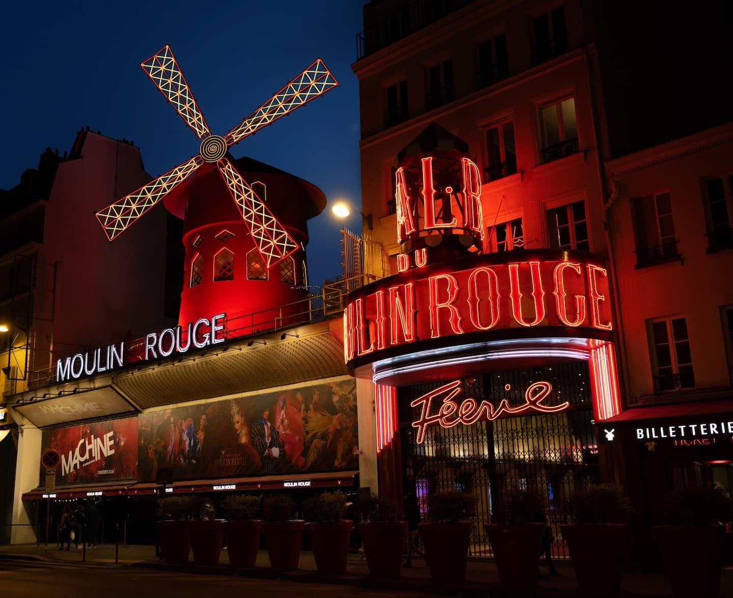 Moulin Rouge iluminado à noite, famoso por seu cabaré e casas temáticas vibrantes.