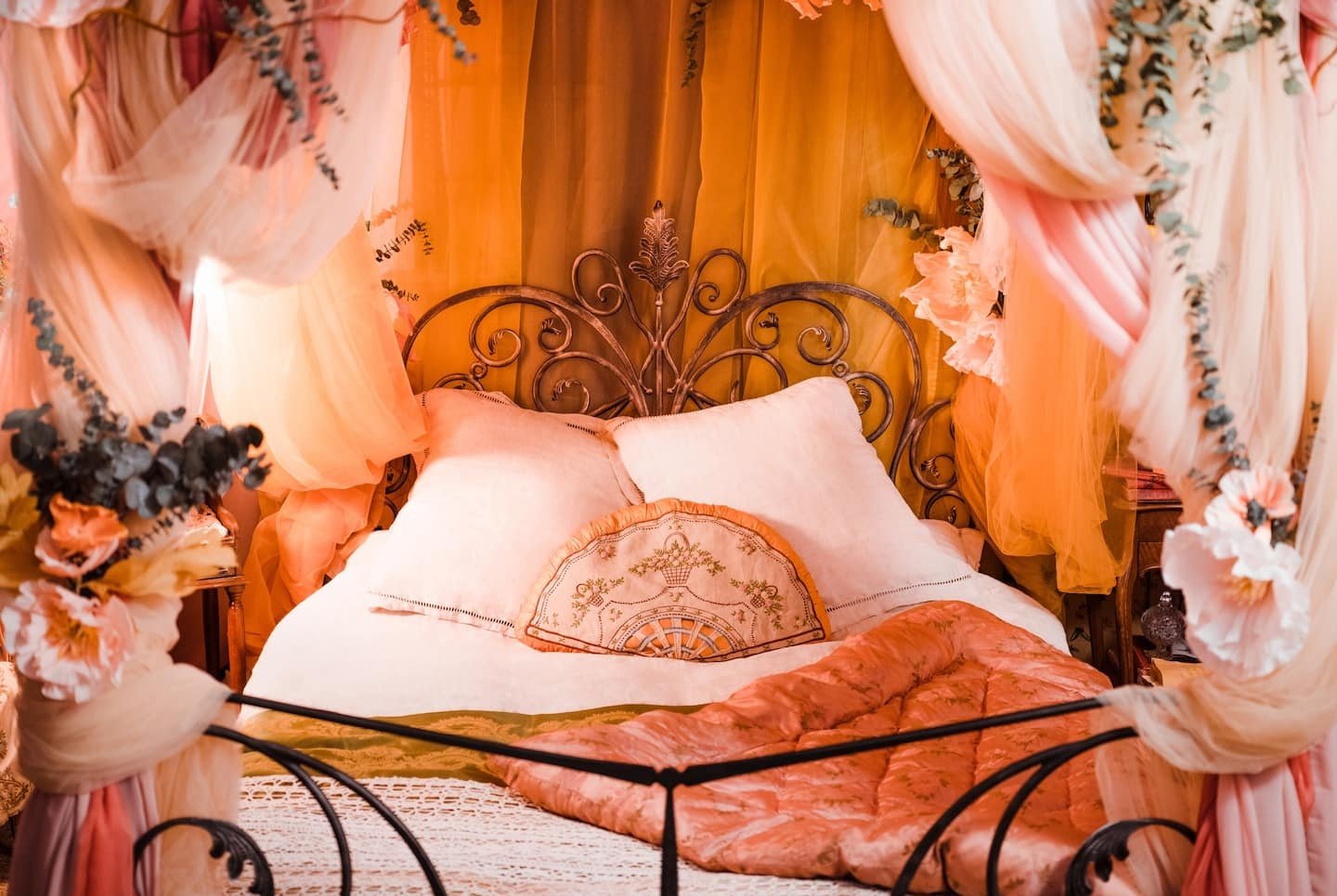 Decoração luxuosa com cama e dossel em tons quentes, evocando um estilo de casas temáticas vintage.