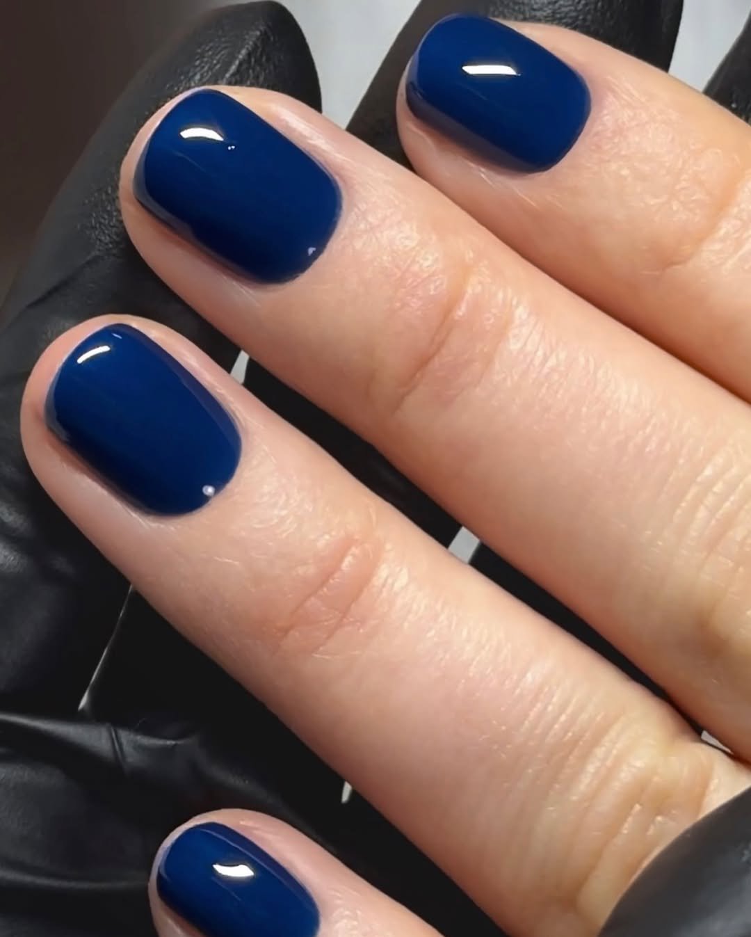 Unhas curtas esmaltadas em azul escuro, destacando elegante cores de esmaltes para unhas curtas