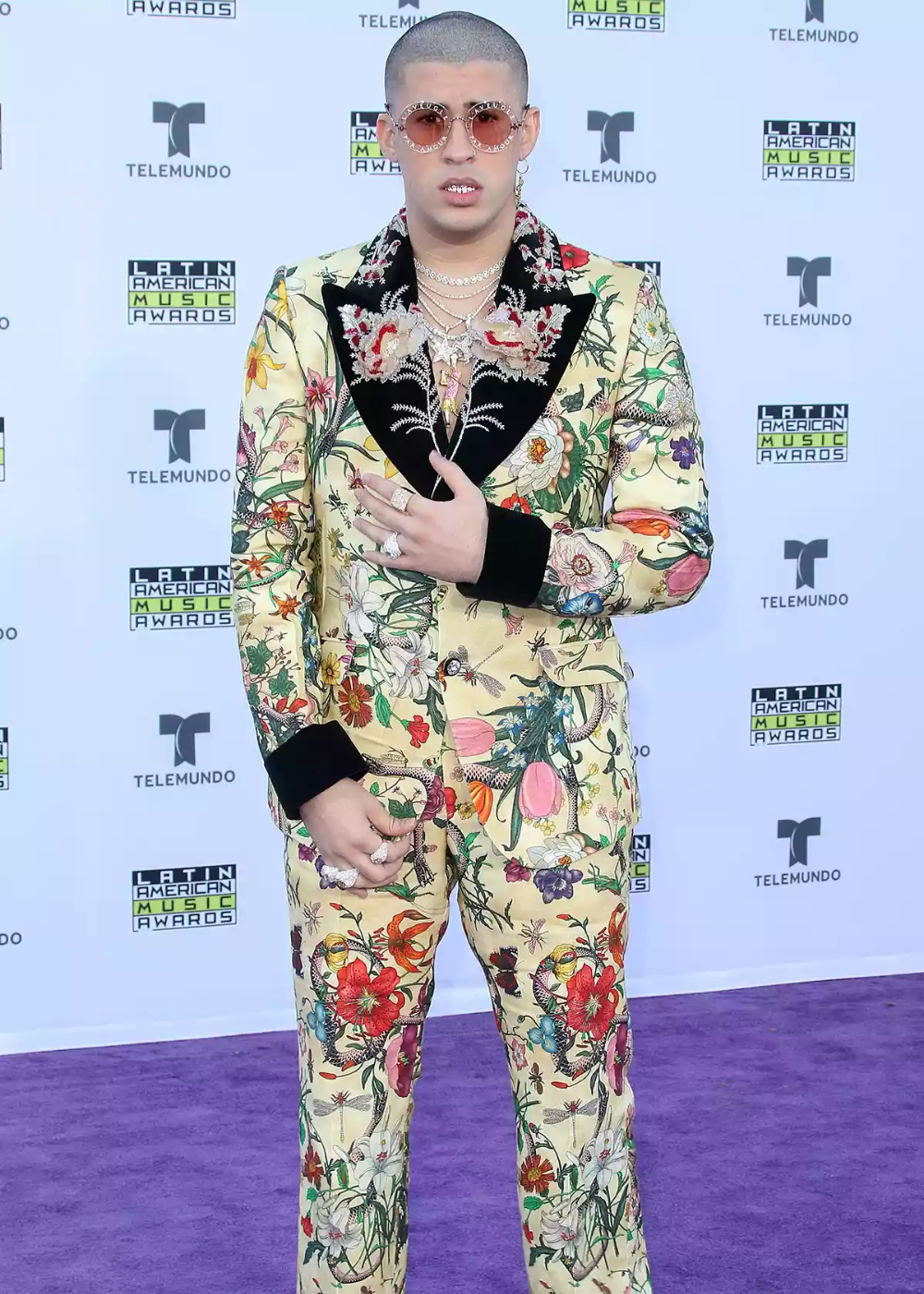 Celebridade com terno floral e óculos de sol no tapete roxo do Latin American Music Awards, Bad Bunny.