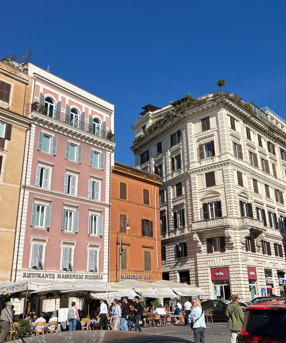 Prédios históricos coloridos e uma animada praça com restaurante ao ar livre, ideal para quem vai viajar pela Europa.