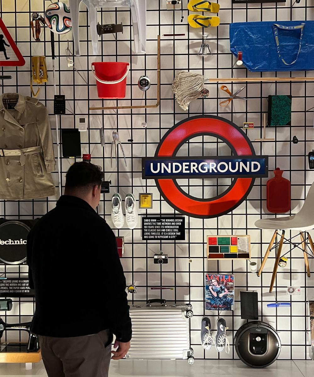 Parede com objetos diversos e símbolo do metrô de Londres, evocando lembranças de viajar pela Europa.