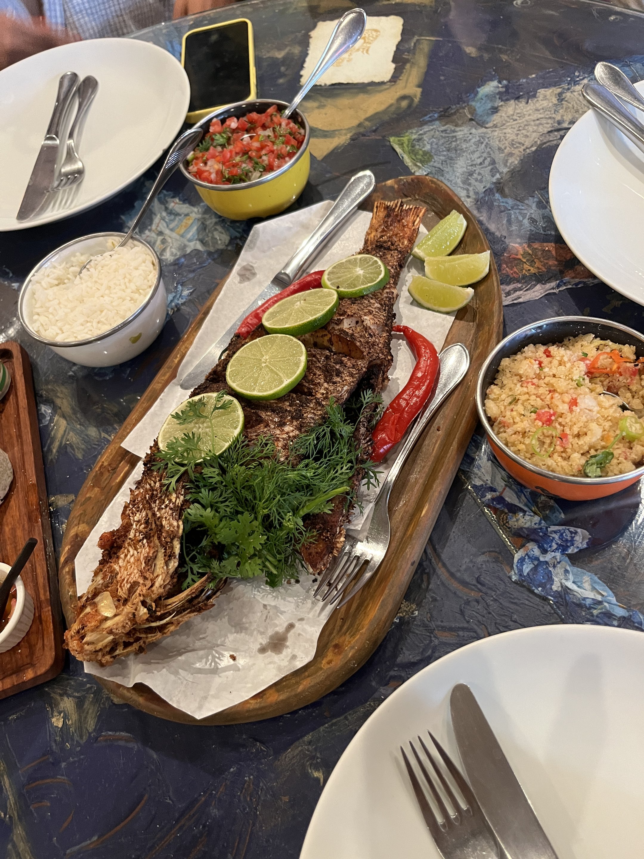 Peixe assado com fatias de limão e ervas em uma tábua, acompanhado de arroz, farofa e vinagrete. sugerindo o que fazer em Salvador