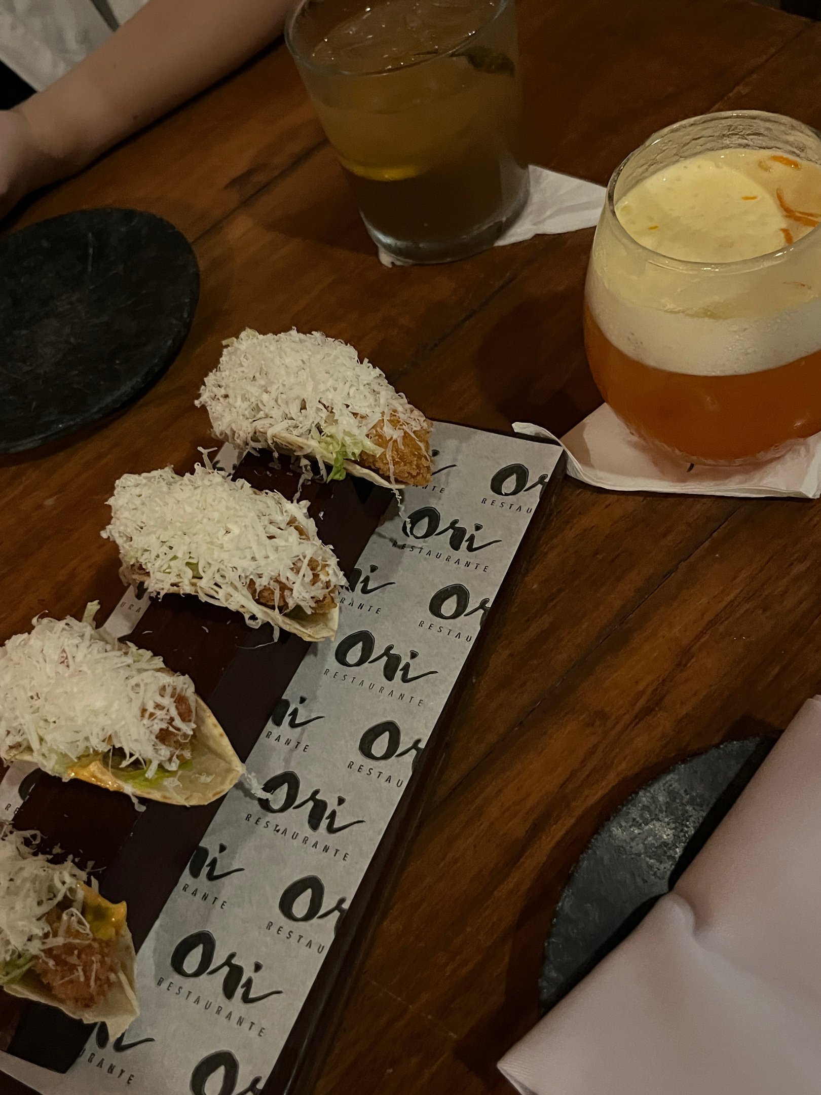 Pratos servidos em restaurante, com taça de bebida e porções de comida cobertas com queijo ralado. sugerindo atividades gastronômicas para fazer em Salvador.