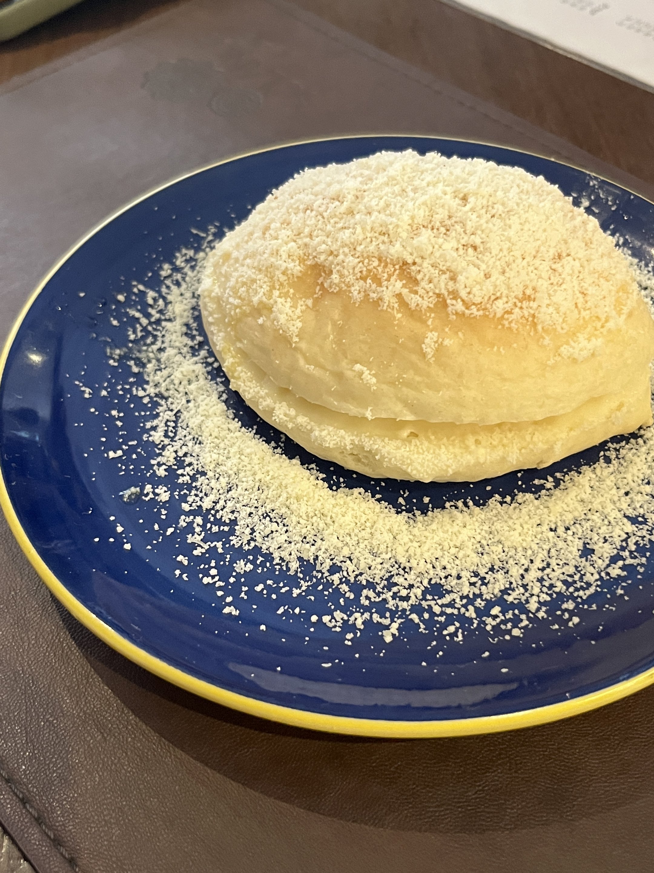 Pão de trigo coberto com queijo ralado em um prato azul, sugerindo o que fazer em Salvador