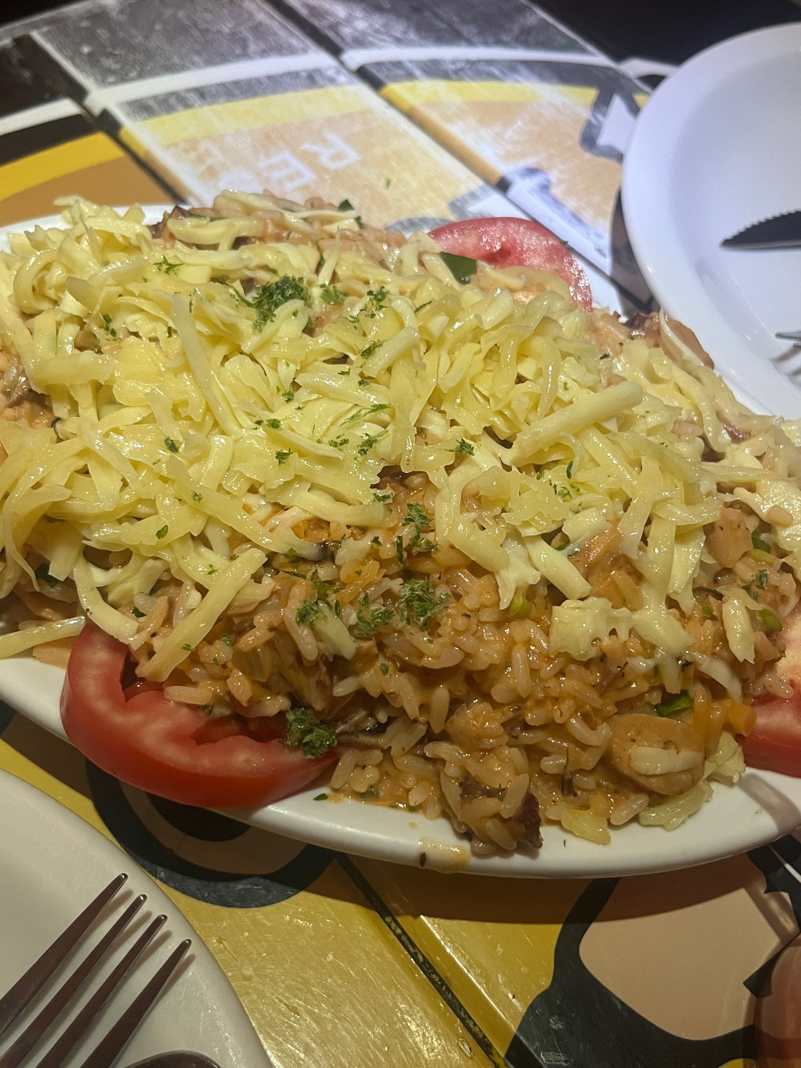 Prato de arroz com queijo ralado e rodelas de tomate, em uma mesa em Salvador.