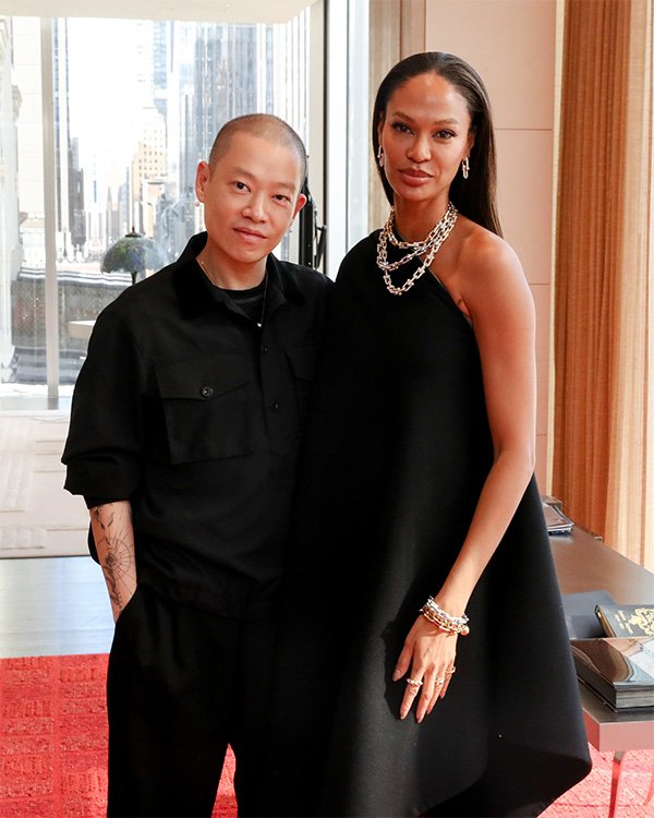 Jason Wu e Joan Smalls posam juntos em uma sala com uma grande janela ao fundo, no dia que Jameel Mohammed ganhou concurso.